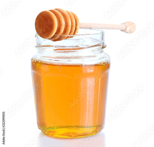 Flüssig gelbe Honig in glass mit holzenem Löffel. Eine Isolierung auf weiss.