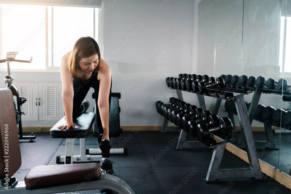 Young beautiful asia woman doing exercises with dumbbell in gym Young beautiful asia woman doing exercises with dumbbell in gym
