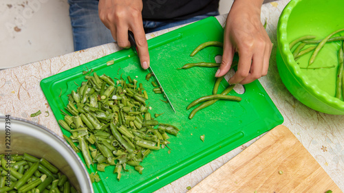 Chef slices green beans on a blackboard