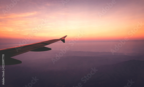 Airplane wings in the sky and a mountains view scene in the sunrise. Travel and adventure.