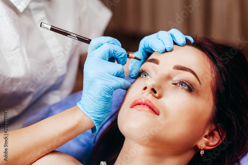 Make-Up. Beautician Hands Doing Eyebrow Tattoo On Woman Face.Permanent Brow Makeup In Beauty Salon. Closeup Of Specialist Doing Eyebrow Tattooing For Female. Cosmetology Treatment. High Resolution