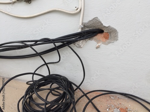 break in the wall with protruding electrical wires, Electric wire sticking out of a white wall, crack hole wall with electric wires