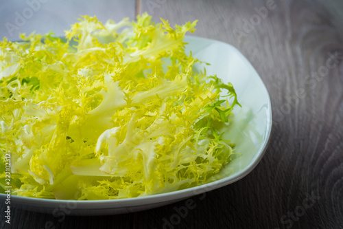 Foto Green frisee lettuce on a white bowl (closeup)