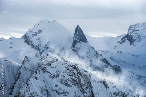 Mt.Sofrudzhu summit and "Sofrudzhu teeth" rock formation in winter cloudy day. Dombay ski resort, Western Caucasus, Karachai-Cherkess, Russia.