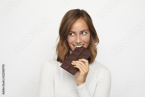 portrait of young woman biting in a pieace of chocolate looks Left