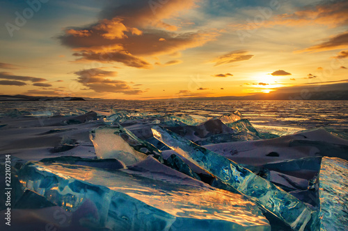 Beautiful colorful sunset over the crystal ice of Baikal lake. Transparent blue Toros Baikal ice is shining through the crack sunset