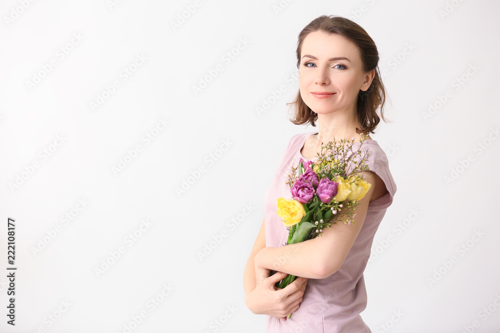Beautiful woman with bouquet of flowers on light background Beautiful woman with bouquet of flowers on light background