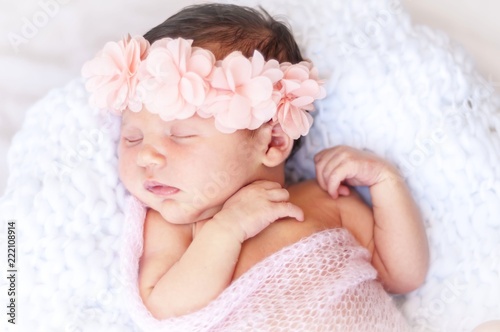 Cute sleeping newborn Caucasian baby girl a pink flower head bow. Sweet infant girl in her sleep. A classical newborn infant photo session. First days of her life concept