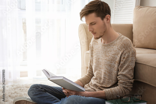 Young man reading book at home