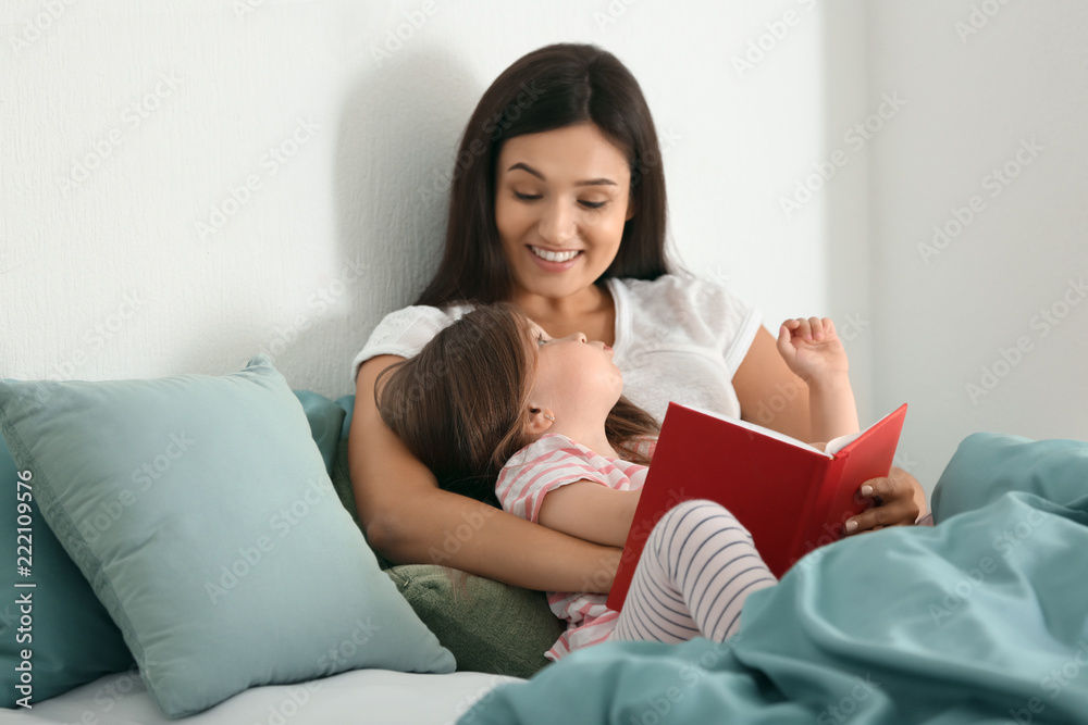 Mother and her daughter reading book together at home