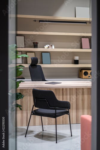 Stylish office with wooden table and shelves