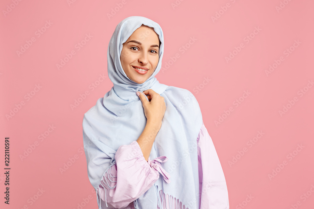 Happy arab woman in hijab. Portrait of smiling girl, posing at pink studio background. Young emotional woman. The human emotions, facial expression concept. Front view. Happy arab woman in hijab. Portrait of smiling girl, posing at pink studio background. Young emotional woman. The human emotions, facial expression concept. Front view.