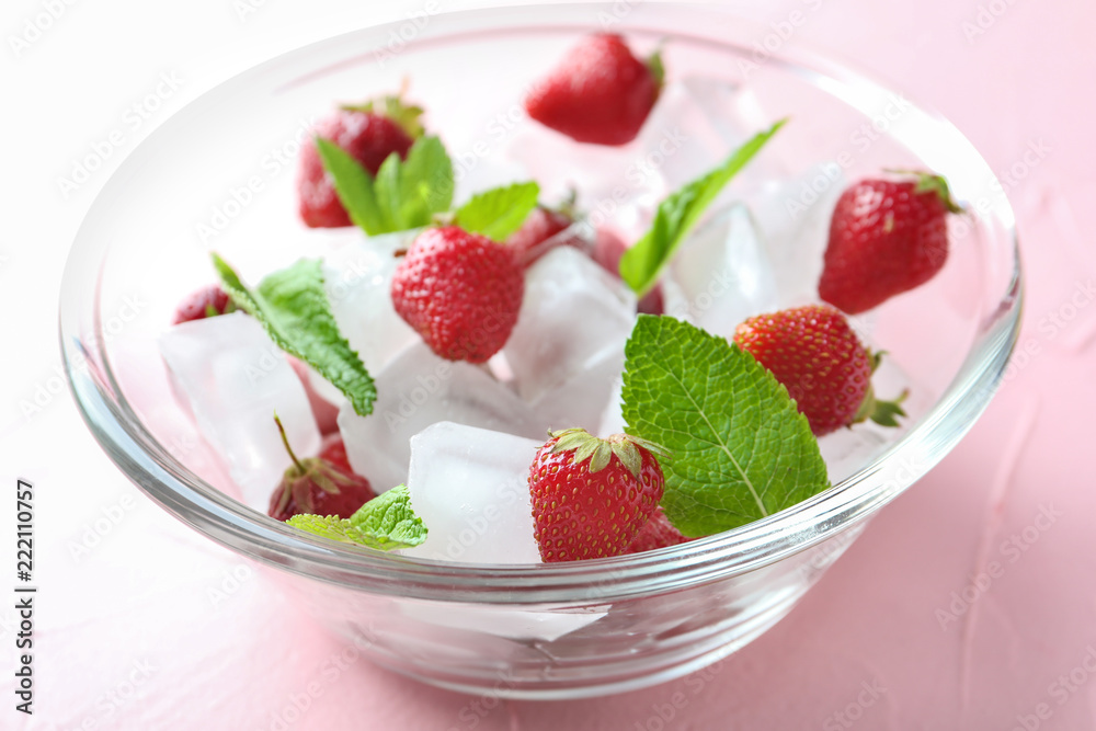 Glass bowl with ice cubes and strawberries on color background Glass bowl with ice cubes and strawberries on color background