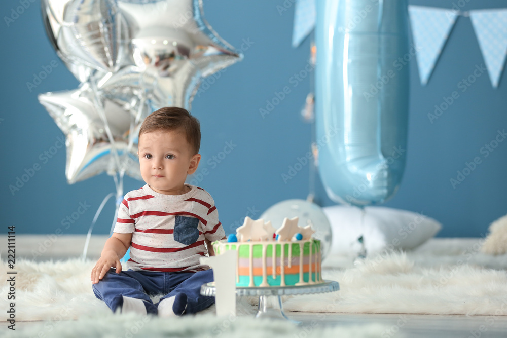 Naklejka premium Cute little boy with birthday cake sitting on fluffy rug in room