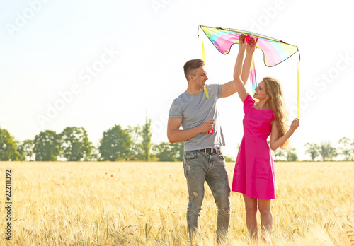 Happy young couple flying kite in a field