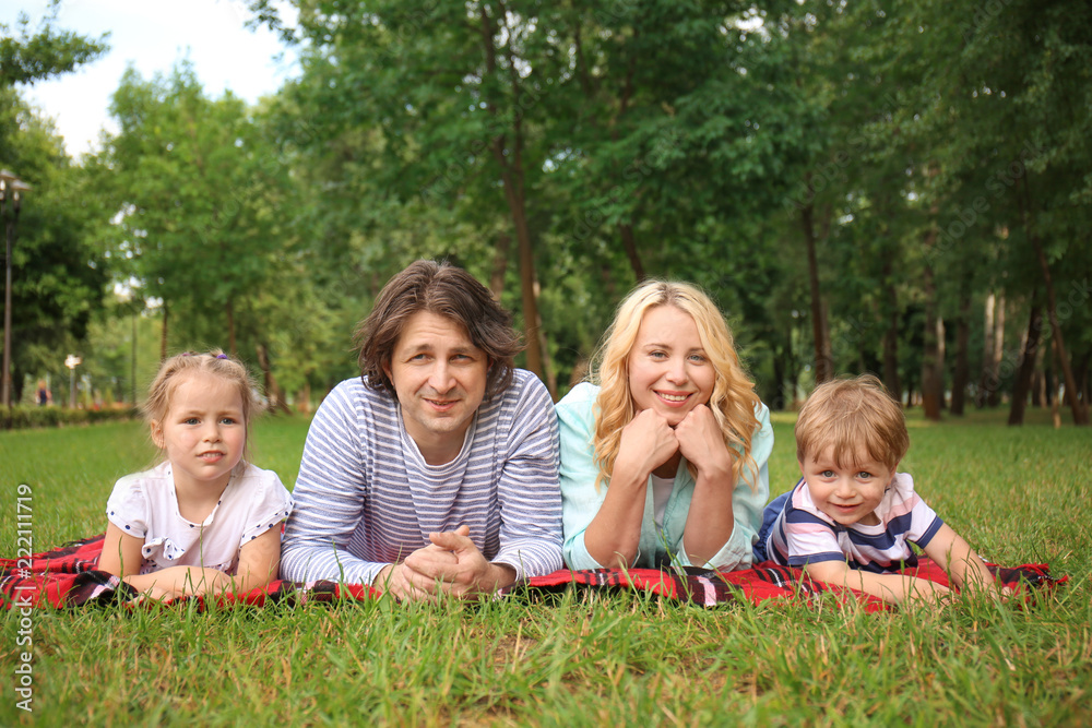 Happy family resting on plaid in park Happy family resting on plaid in park