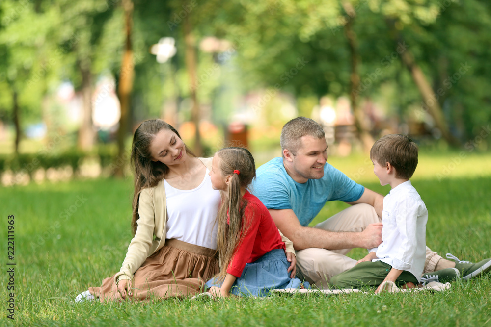 Happy family resting on plaid in park