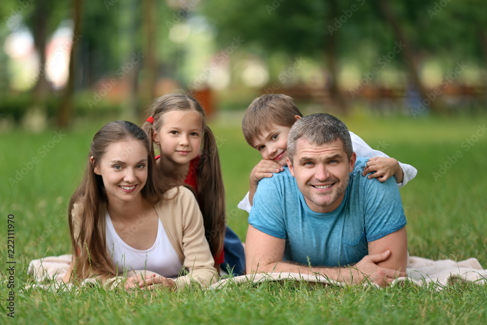 Happy family resting on plaid in park