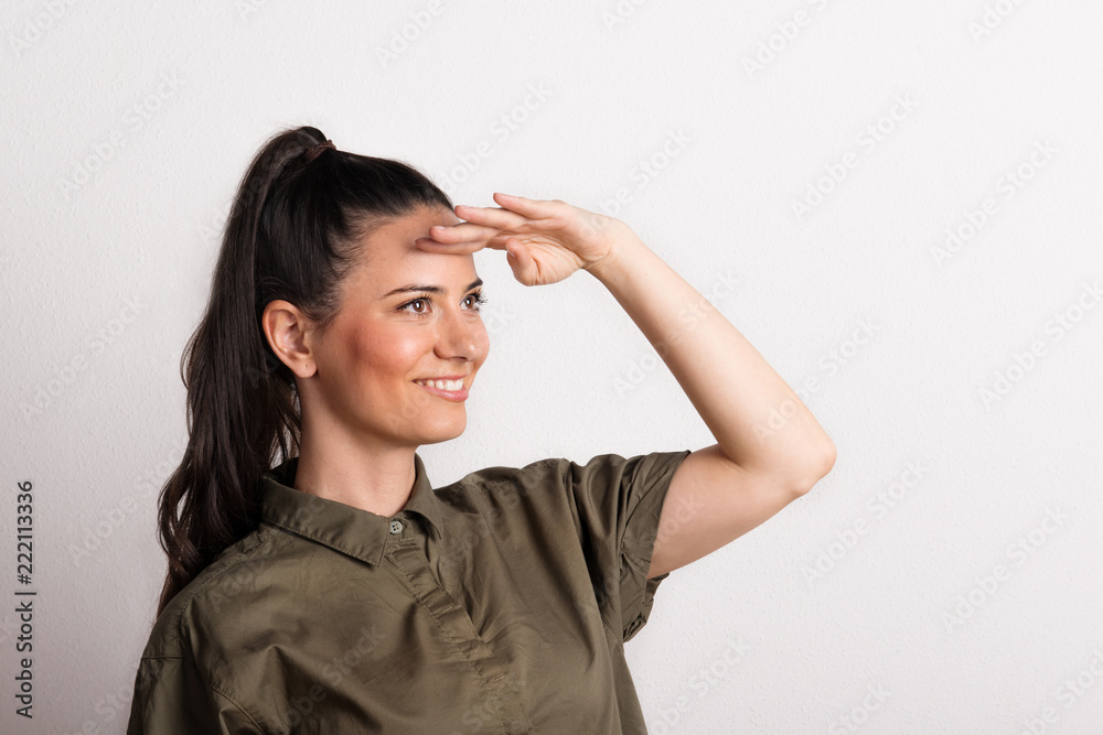 Portrait of a young beautiful woman looking far away with hand at her forehead. Portrait of a young beautiful woman looking far away with hand at her forehead.