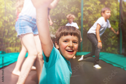 Happy boy jumping on trampoline with his friends
