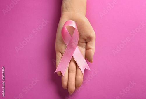 Woman holding pink ribbon on color background. Breast cancer awareness concept