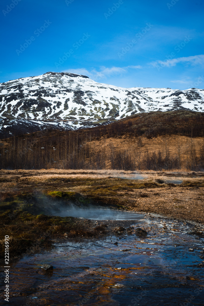 Hot Springs in Geysir Geothermal Field, Iceland with Snowy Mountain in the Background