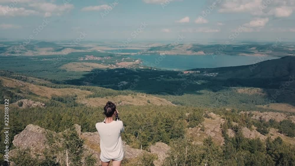 Drone flight over the Ural mountains, a young brave woman walking around and making a photo shoots of lakes and villages on the background, ski resort in winter, Russia, Bashkortostan republic Drone flight over the Ural mountains, a young brave woman walking around and making a photo shoots of lakes and villages on the background, ski resort in winter, Russia, Bashkortostan republic