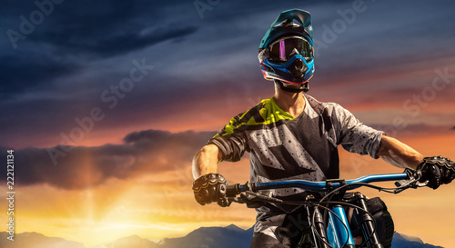 Mountain biker on sunset trail. Male cyclist portrait in sport helmet