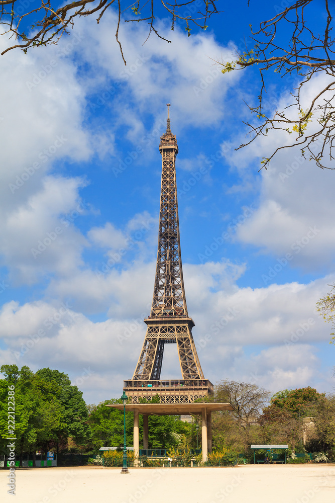 Beautiful vibrant spring view of the Eiffel tower in Paris, France, with a blue sky and some clouds