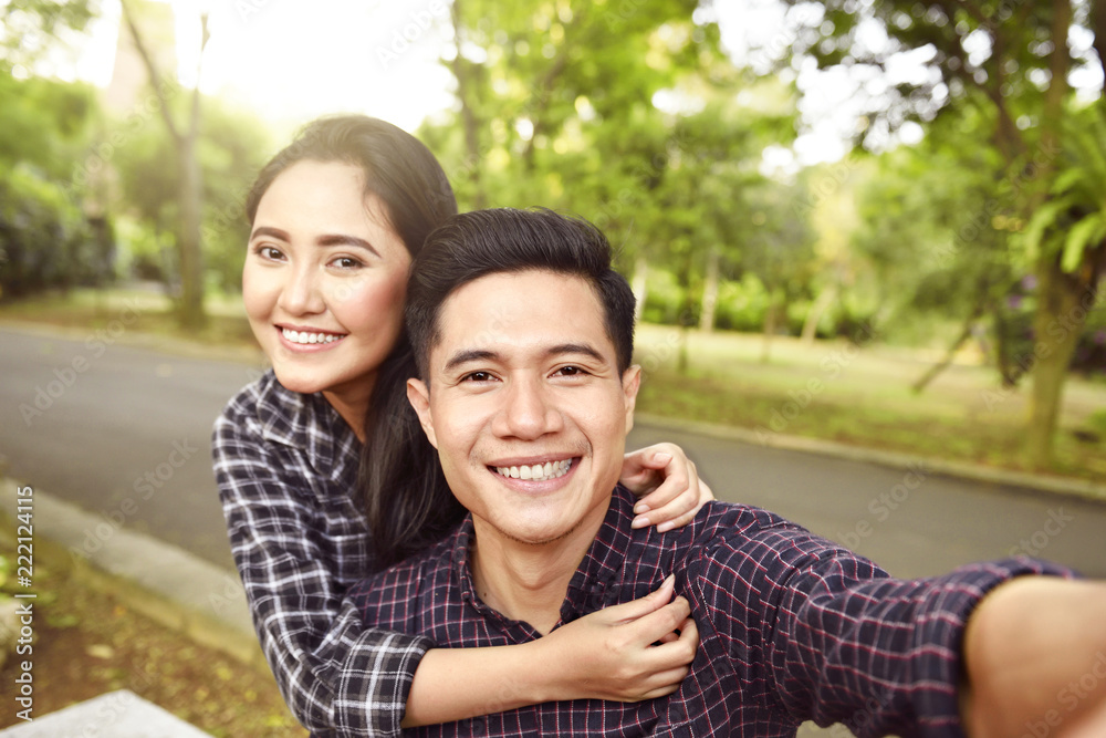 Two asian lovers making a selfie on phone Two asian lovers making a selfie on phone