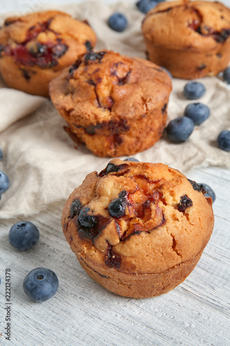 Tasty blueberry muffins on white wooden table