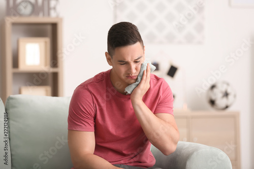 Young man suffering from tooth ache at home