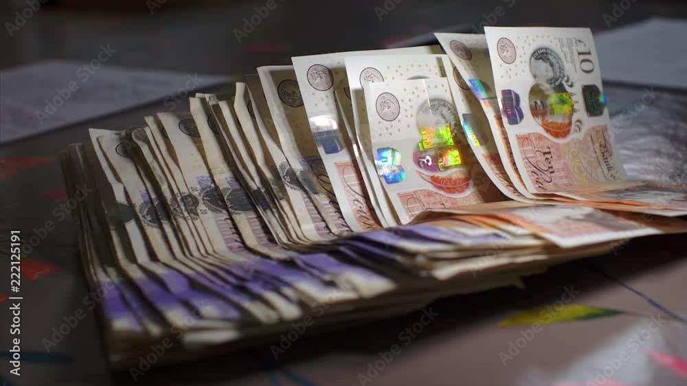Money falling from above onto a table, pushed across by a man wearing a wedding ring.