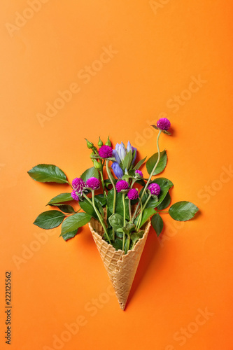Fototapeta Naklejka Na Ścianę i Meble -  Waffle cone with beautiful flowers on color background