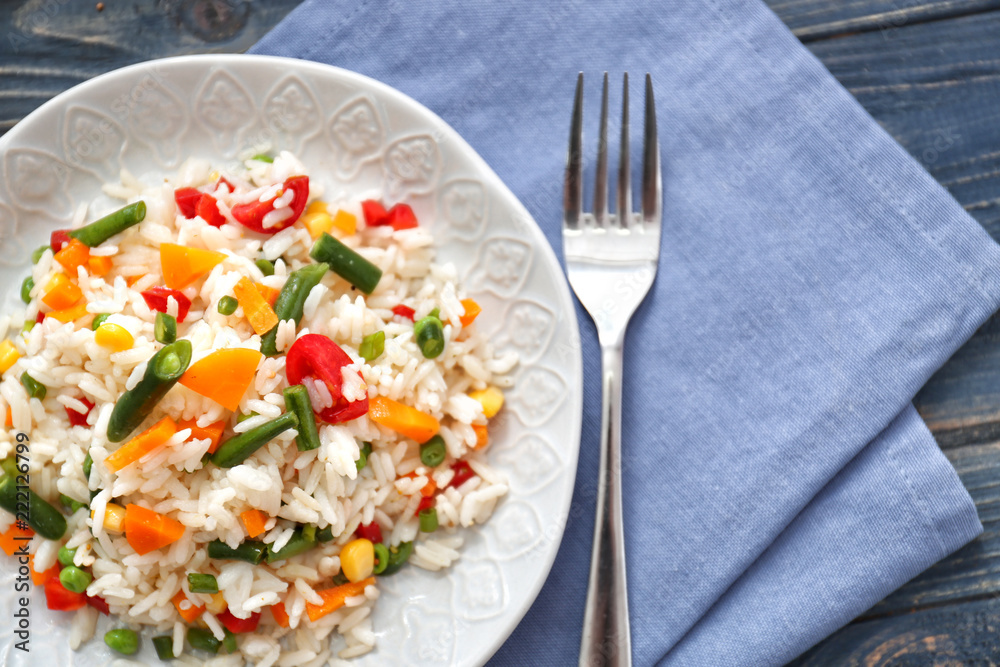 Plate with tasty boiled rice and vegetables on wooden table Plate with tasty boiled rice and vegetables on wooden table