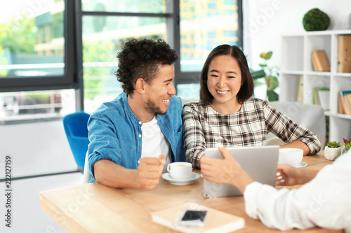 Happy interracial couple with real estate agent in office