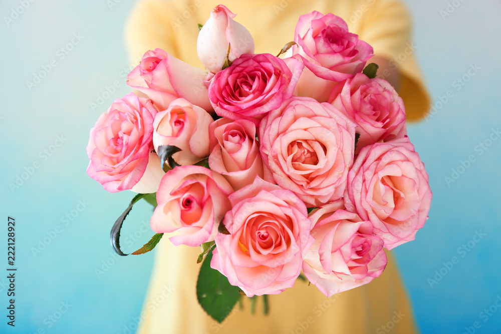 Woman holding bouquet of beautiful roses on color background