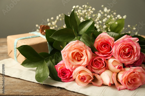 Beautiful roses with gift box on wooden table