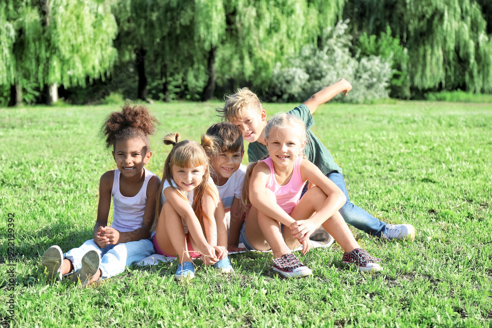 Fototapeta premium Cute little children sitting on green grass outdoors