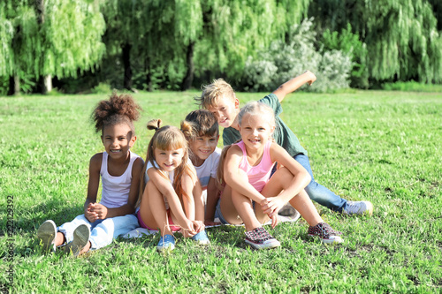 Cute little children sitting on green grass outdoors © Pixel-Shot