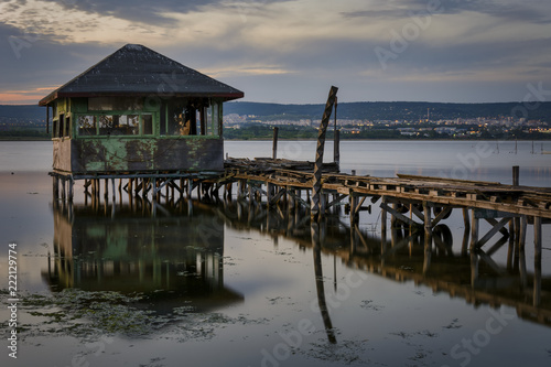 wooden Fishing hut in a lake with pier and fishing net at sunset. © CLement