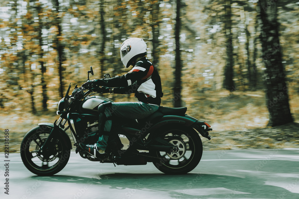 Biker In Helmet Is Riding On Highway In A Forest.
