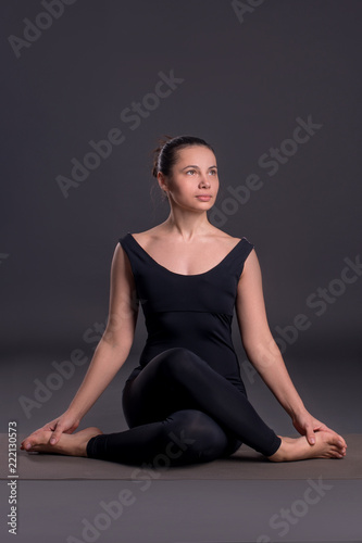Young calm beautiful woman of the brunette with long hair wearing black sportswear. lilac overalls. in yoga pose