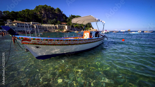 Taormina, Italy - July 9, 2018: Typical Sicilian wooden boat moored in the transparent water.