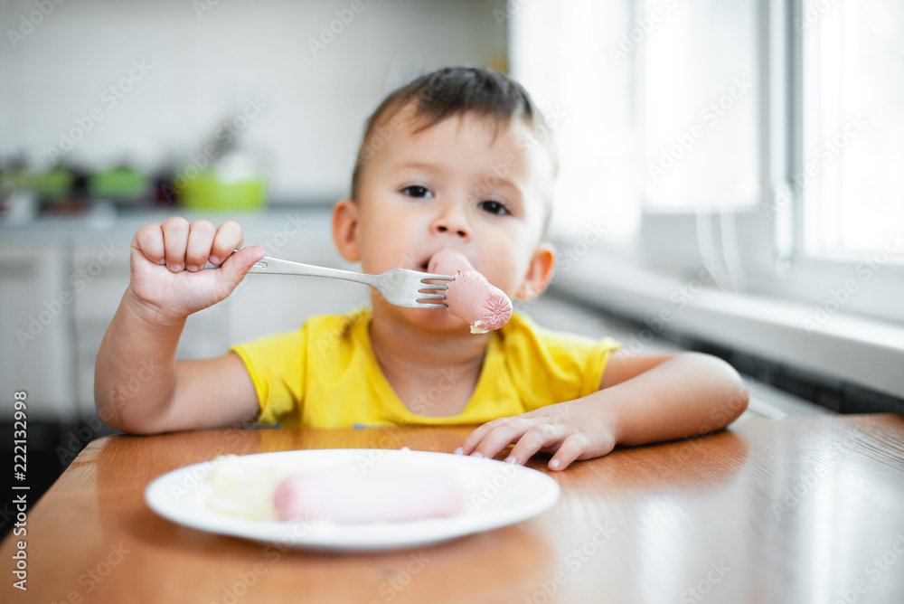 child in the kitchen eating sausage and mashed potatoes child in the kitchen eating sausage and mashed potatoes