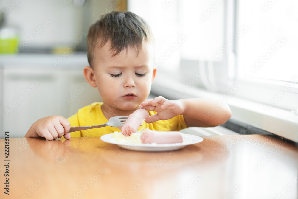 child in the kitchen eating sausage and mashed potatoes child in the kitchen eating sausage and mashed potatoes