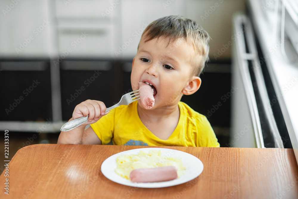 child in the kitchen eating sausage and mashed potatoes child in the kitchen eating sausage and mashed potatoes