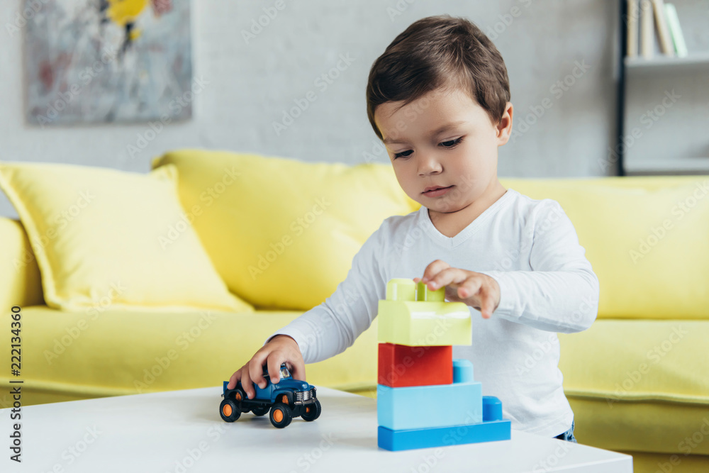 little boy playing with constructor blocks and toy car on table at home little boy playing with constructor blocks and toy car on table at home