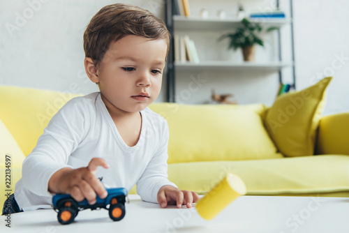 adorable kid playing with blue toy car at home