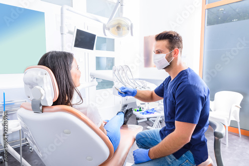 Młody dentysta taktuje żeńskiego pacjenta w stomatologicznym studiu